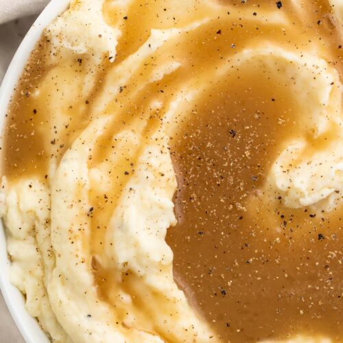 Top-down view of a large bowl of mashed potatoes topped with rich brown paleo gravy.