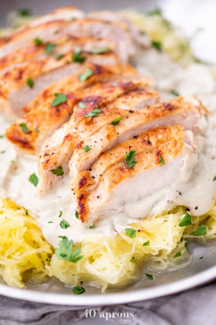 Closeup of healthy Whole30 chicken alfredo with spaghetti squash in a skillet topped with parsley