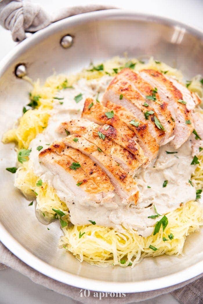 Healthy Whole30 chicken alfredo with spaghetti squash in a skillet topped with parsley