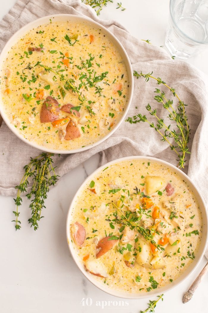 Overhead shot of two bowls of Instant Pot healthy chicken pot pie soup garnished with parsley and thyme leaves