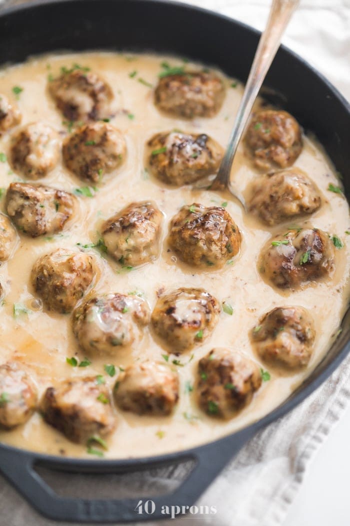 Closeup of Paleo Swedish meatballs in creamy Swedish meatballs sauce in a cast iron skillet overhead