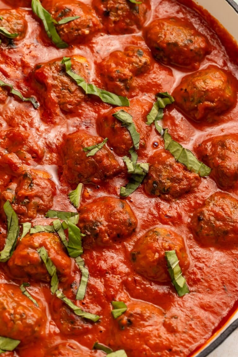 Close-up of Whole30 Italian meatballs in creamy tomato sauce, showing texture and fresh basil garnish.