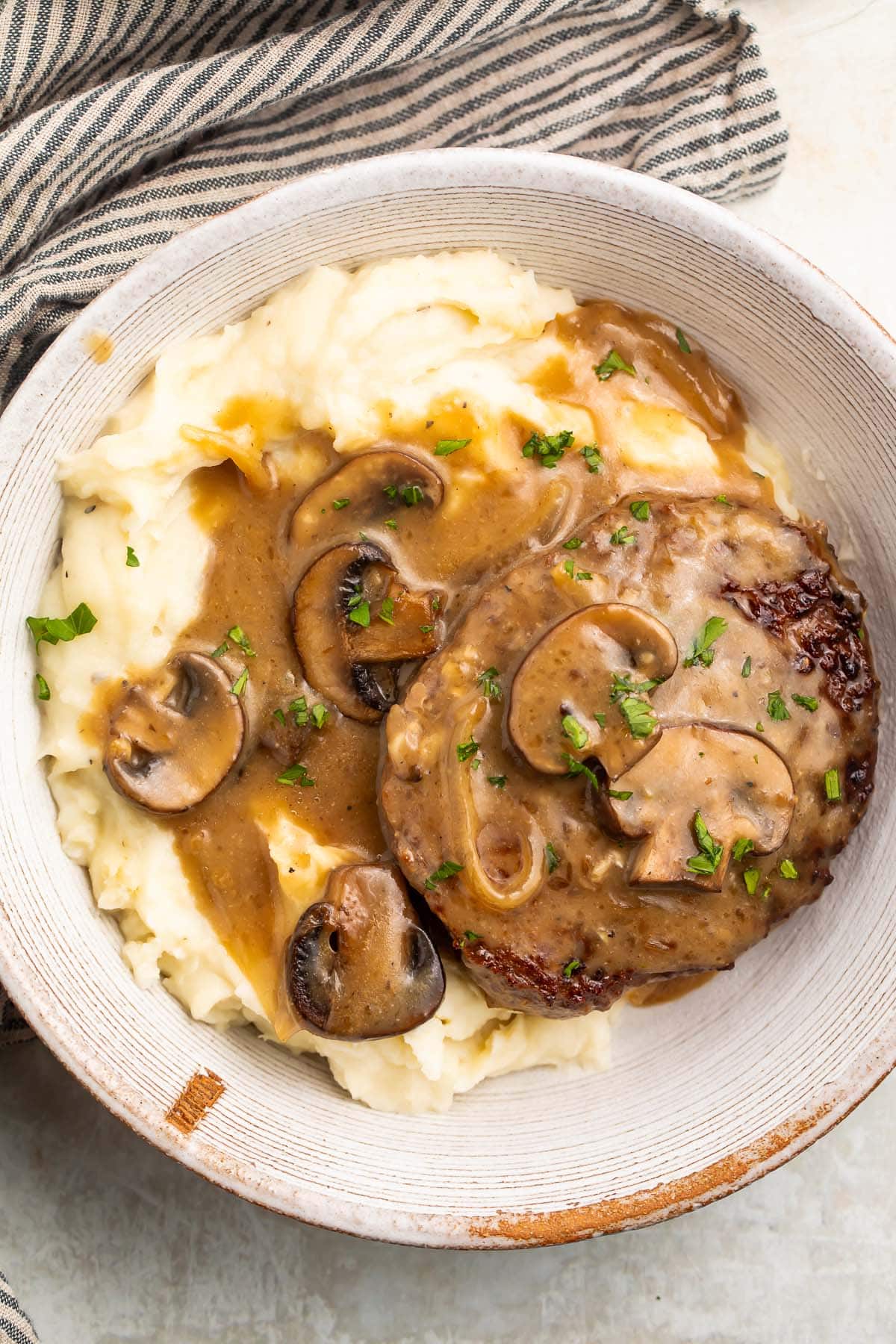 A large bowl of Whole30 salisbury steak and mashed potatoes smothered in plenty of brown gravy.