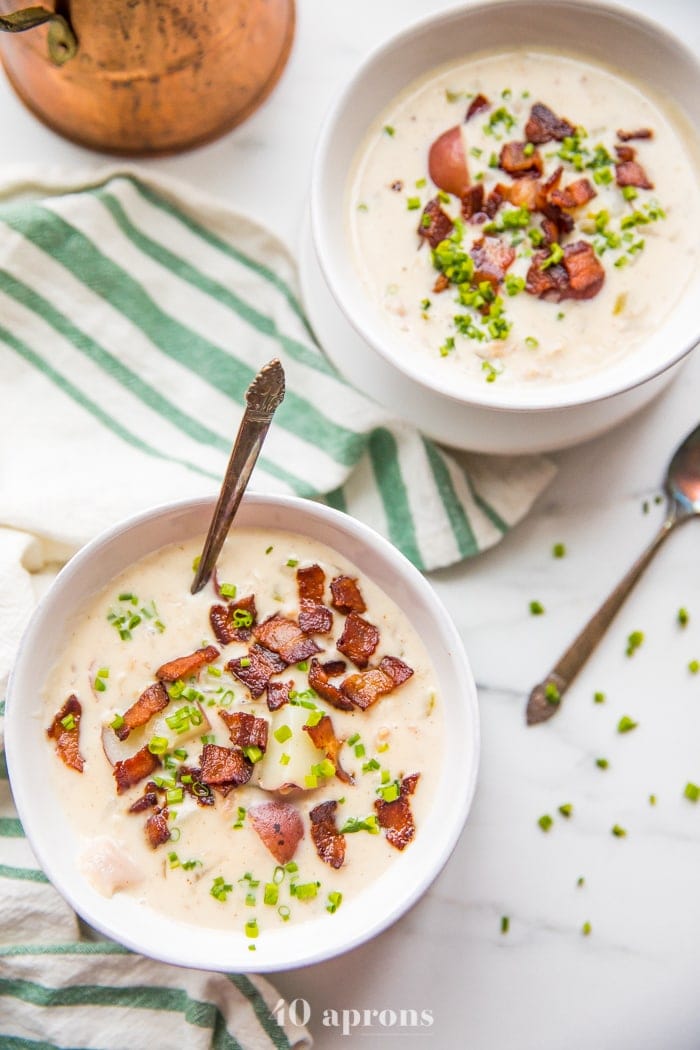 Overhead shot of healthy creamy Whole30 clam chowder in two bowls with bacon and chives