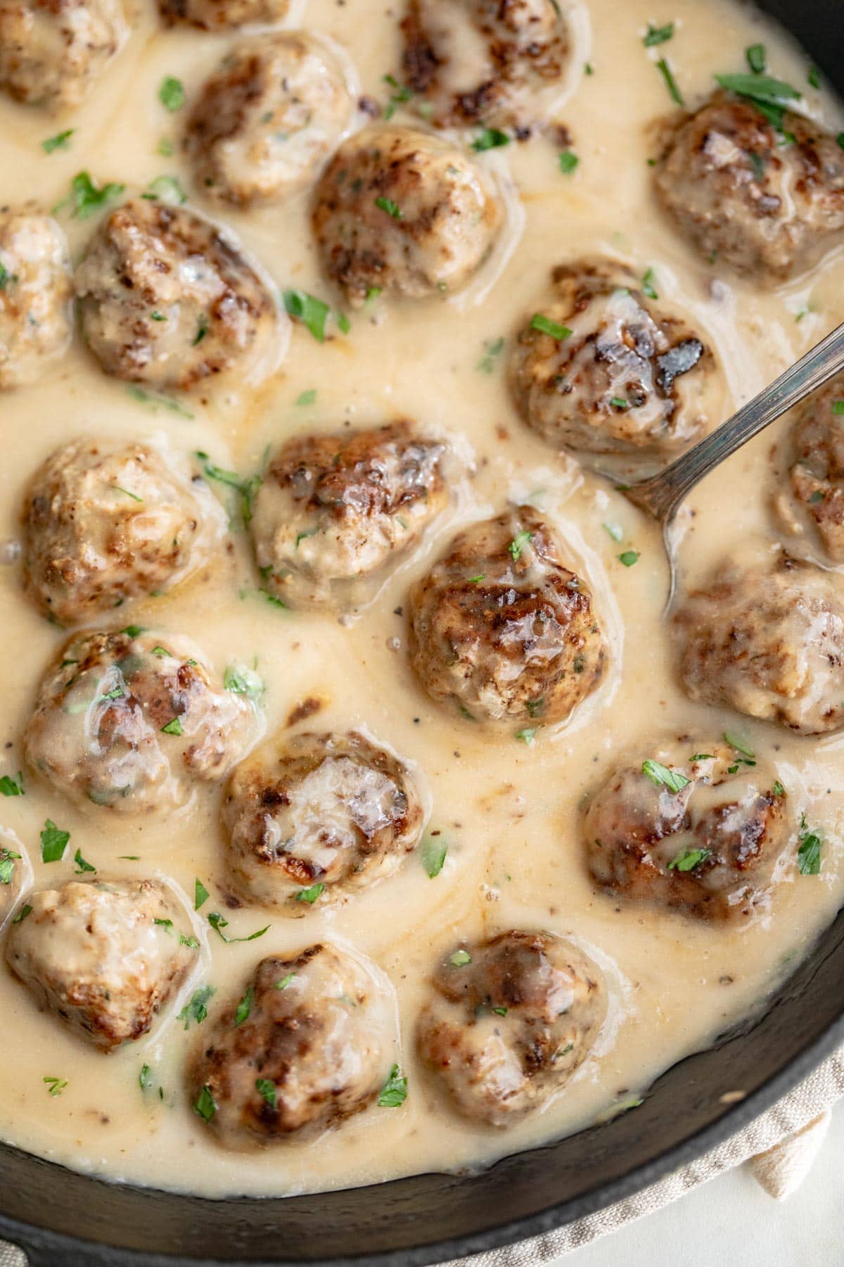 Whole30 Swedish meatballs in a large cast-iron skillet with plenty of creamy sauce.