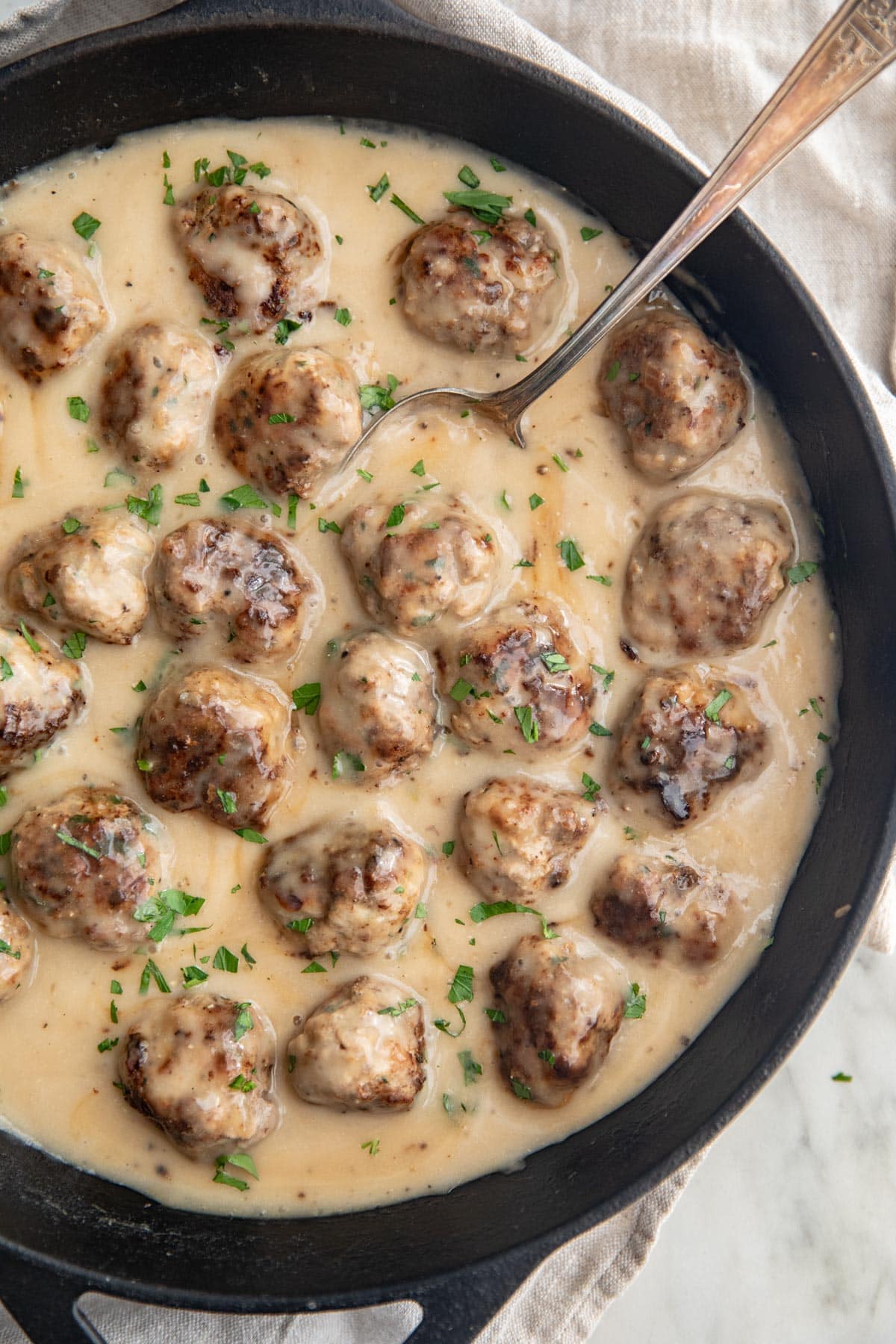 Whole30 Swedish meatballs in a large cast-iron skillet with plenty of creamy sauce.