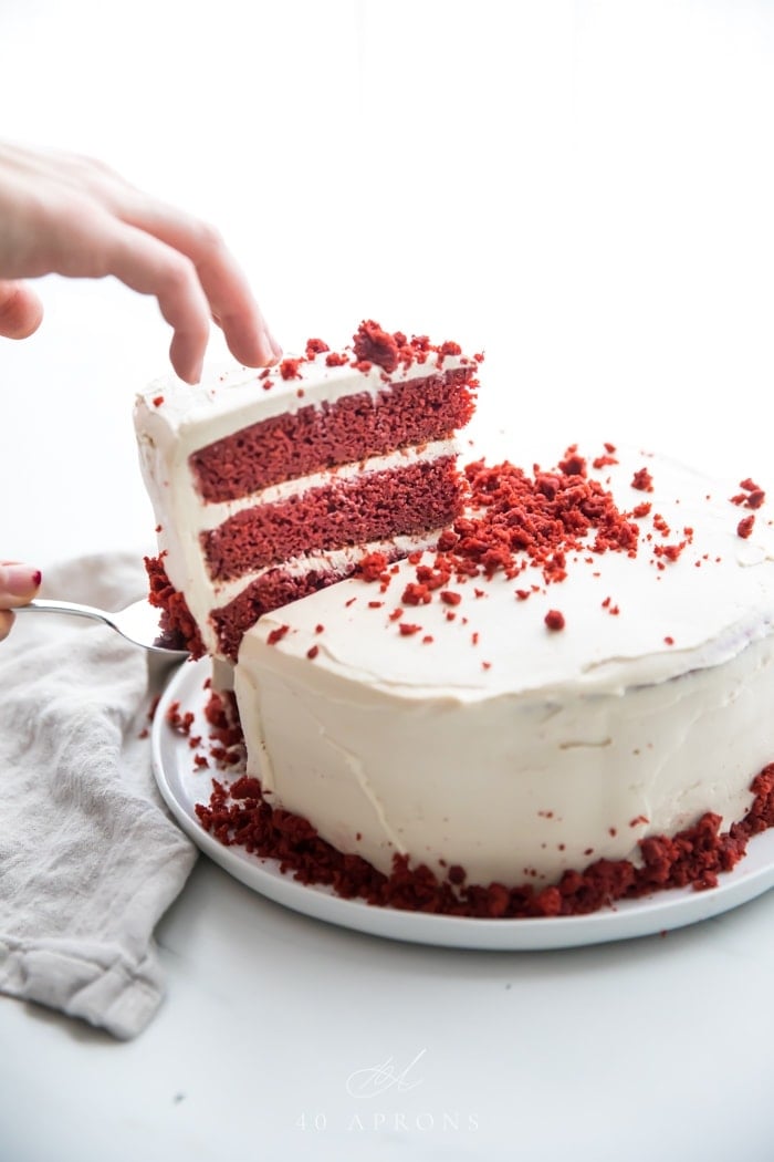 Slice of three layer gluten free red velvet being lifted out of whole cake