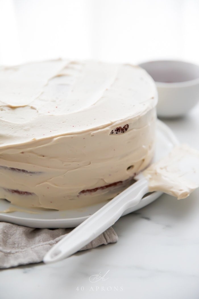 A crumb coat on a gluten free red velvet layer cake with paleo cream cheese frosting