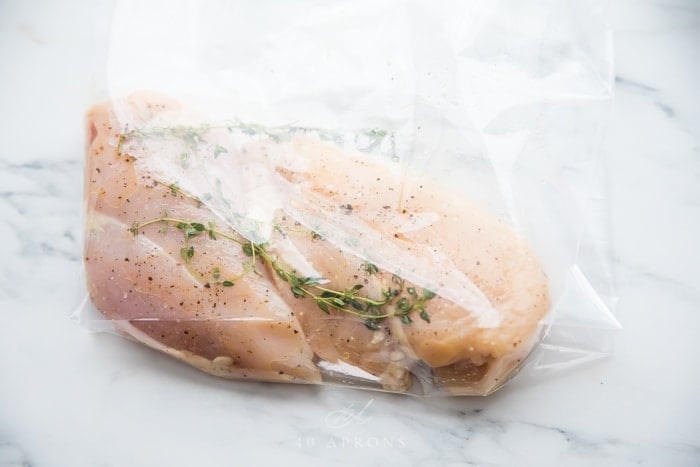 Place chicken breasts and herbs in a Ziploc bag or vacuum seal