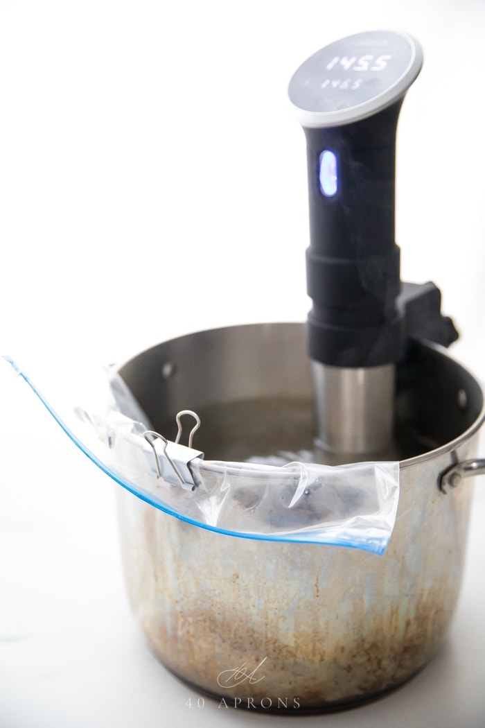 A pot with a water bath and a Ziploc bag with Anova sous vide precision cooker attached