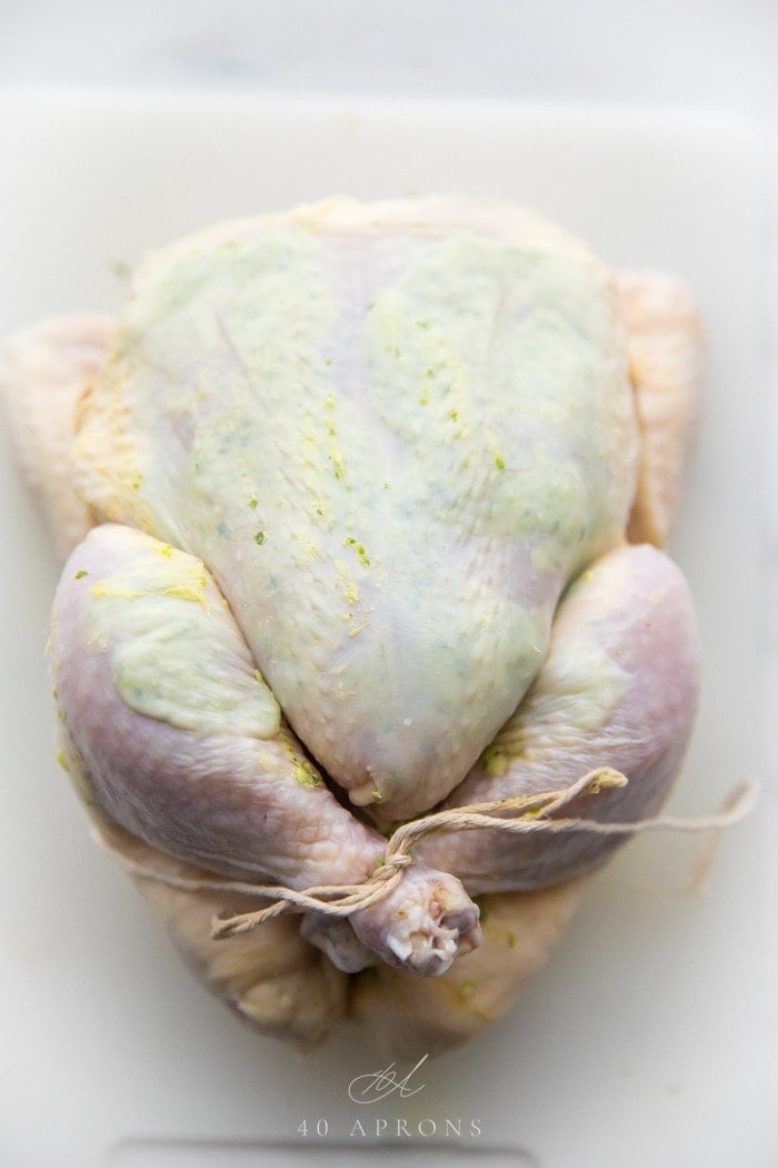 A whole chicken with herb garlic butter stuffed under the skin, trussed