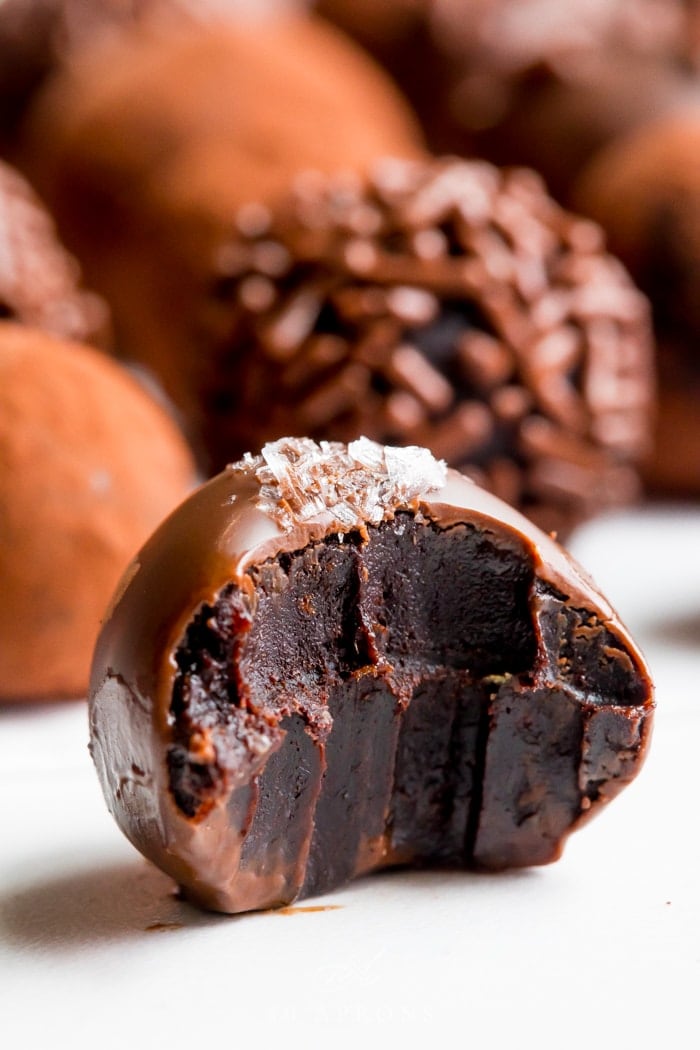 A close up of a vegan chocolate truffle coated in chocolate with more in the background