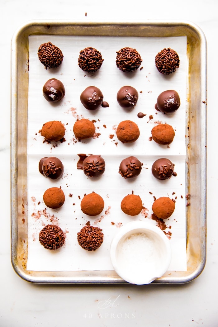 Several vegan truffles with different coatings on a parchment lined baking sheet