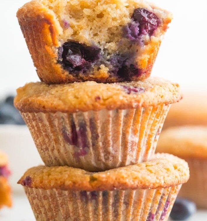 A stack of three paleo blueberry muffins with bite out of one