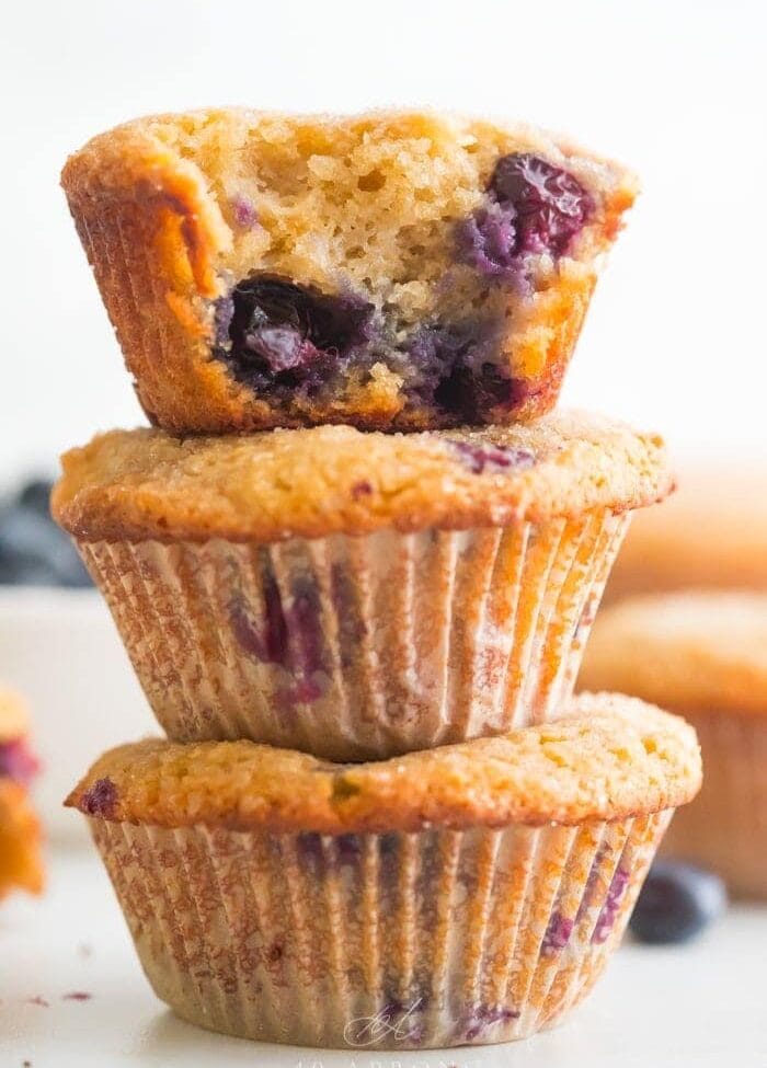 A stack of three paleo blueberry muffins with bite out of one