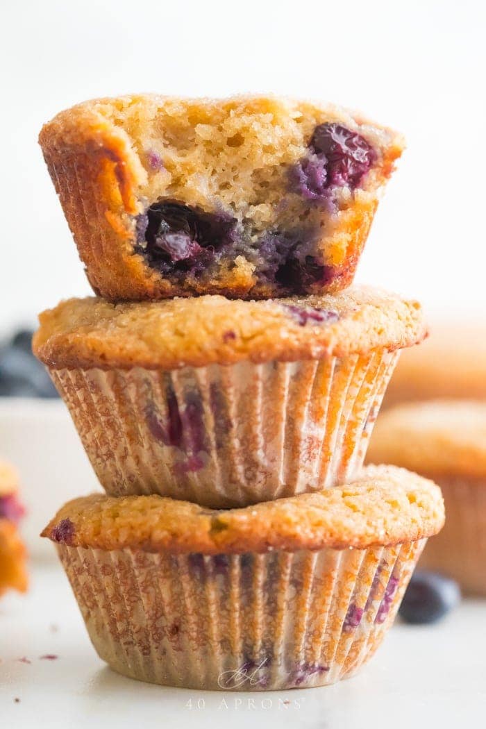 A stack of three paleo blueberry muffins with bite out of one