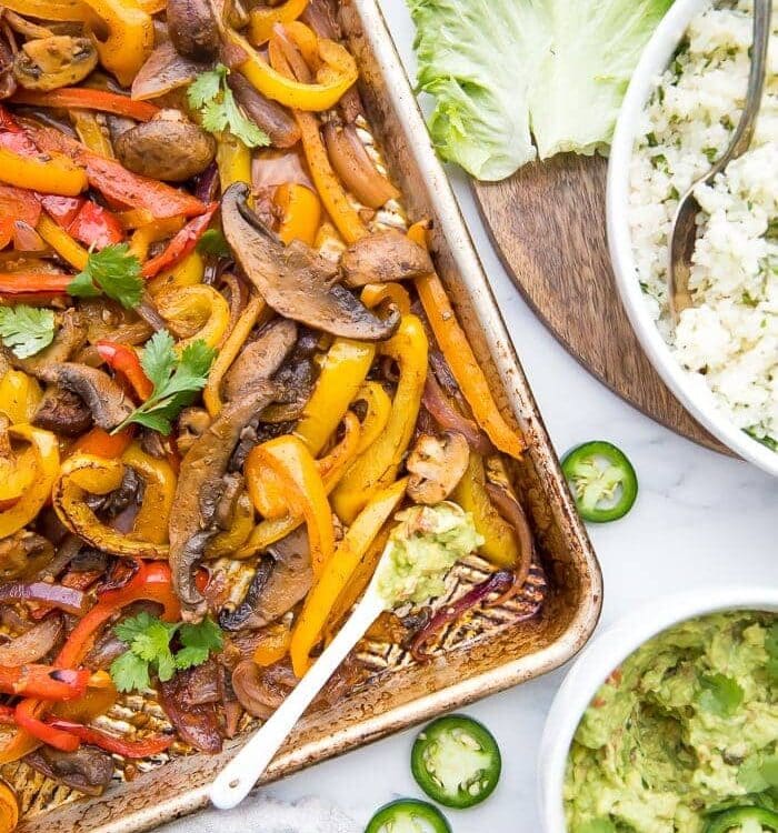 Overhead of Vegetarian sheet pan fajitas with a bowl of cauliflower rice and bowl of guacamole to the side