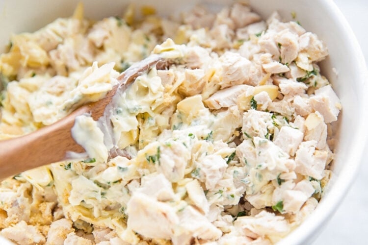 Tarragon chicken salad in a large mixing bowl with a large wooden mixing spoon.