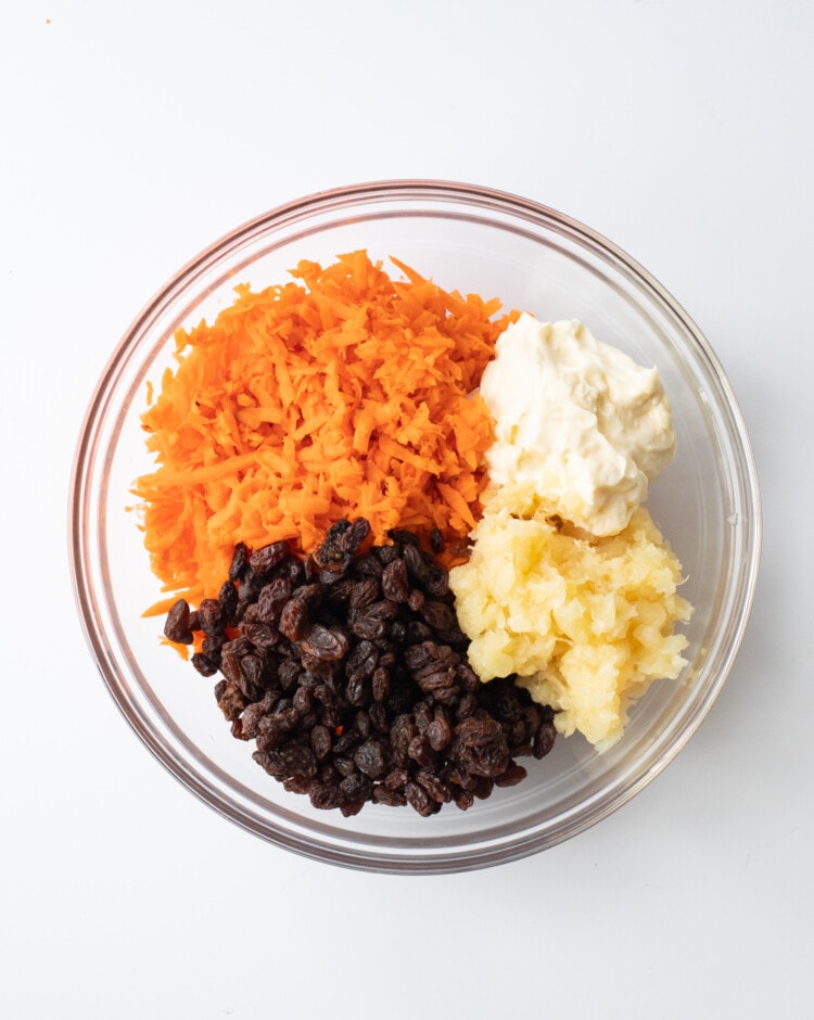 Ingredients for carrot raisin salad in one glass bowl