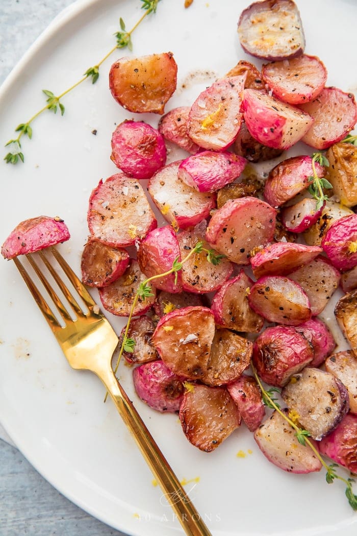 A plate of roasted radishes with a gold fork