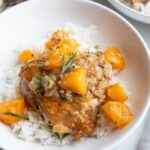 Apricot chicken over white rice in a white bowl