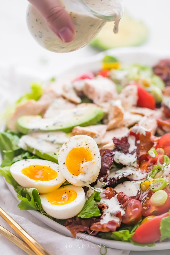 Ranch dressing drizzling over a classic chicken healthy cobb salad
