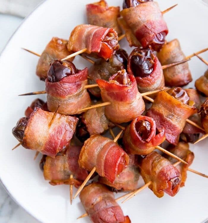 Bacon wrapped dates on a white plate