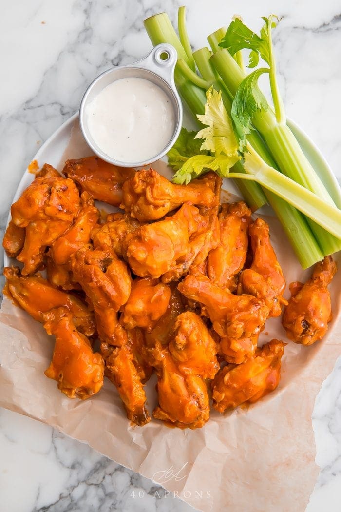 Crockpot chicken wings on parchment paper with celery and blue cheese