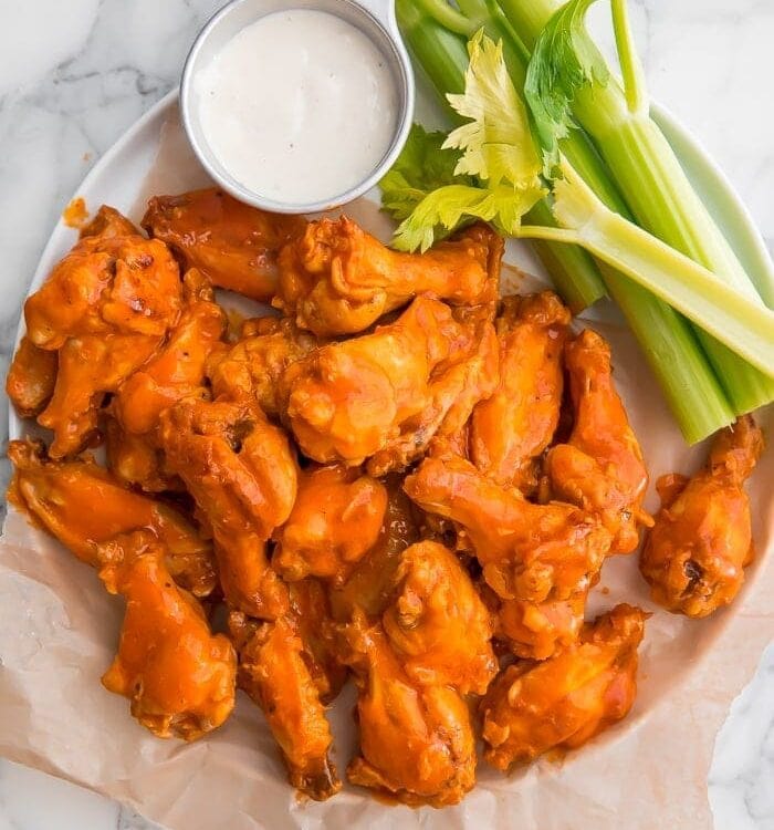 Crockpot chicken wings on parchment paper with celery and blue cheese