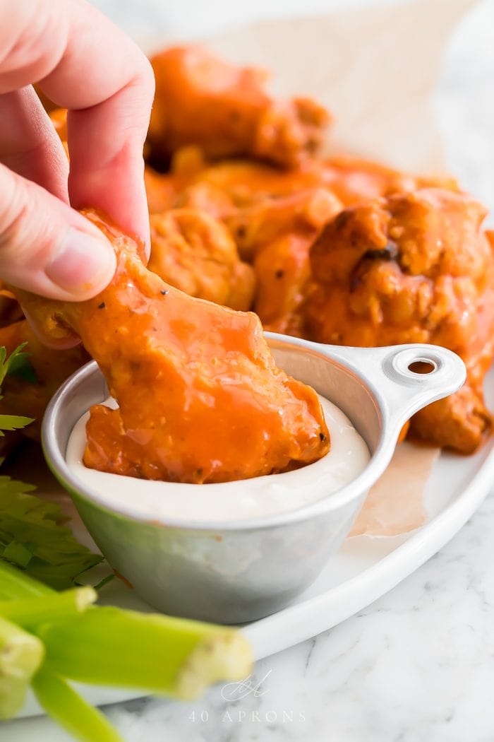 A chicken wing being dipped in sauce