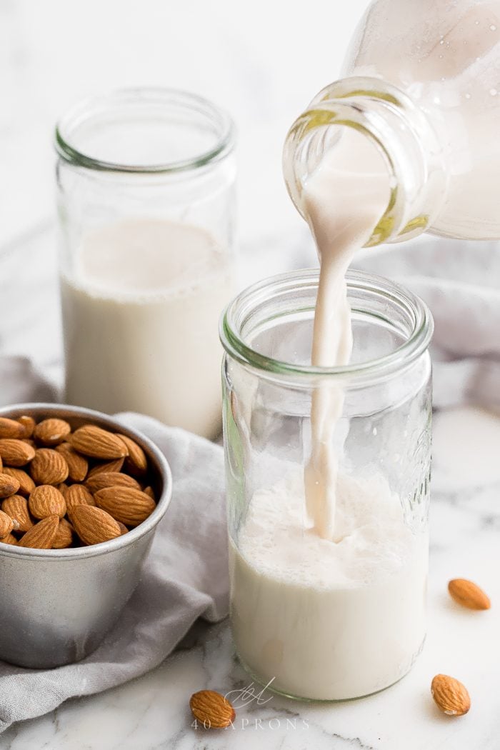 Homemade almond milk pouring into a jar