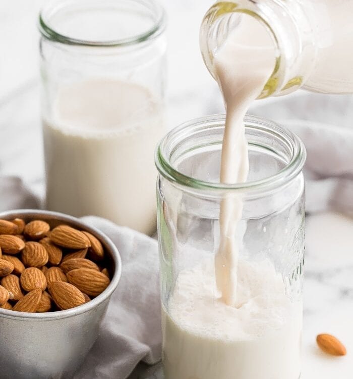 Homemade almond milk pouring into a jar