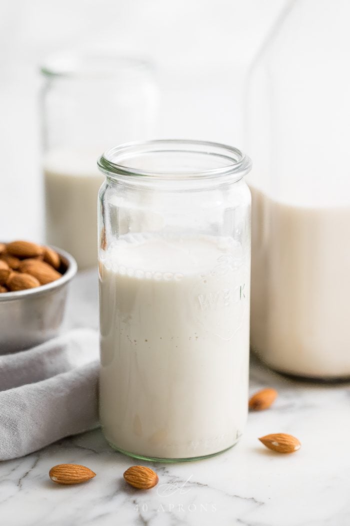 Homemade almond milk in a jar with other containers in background