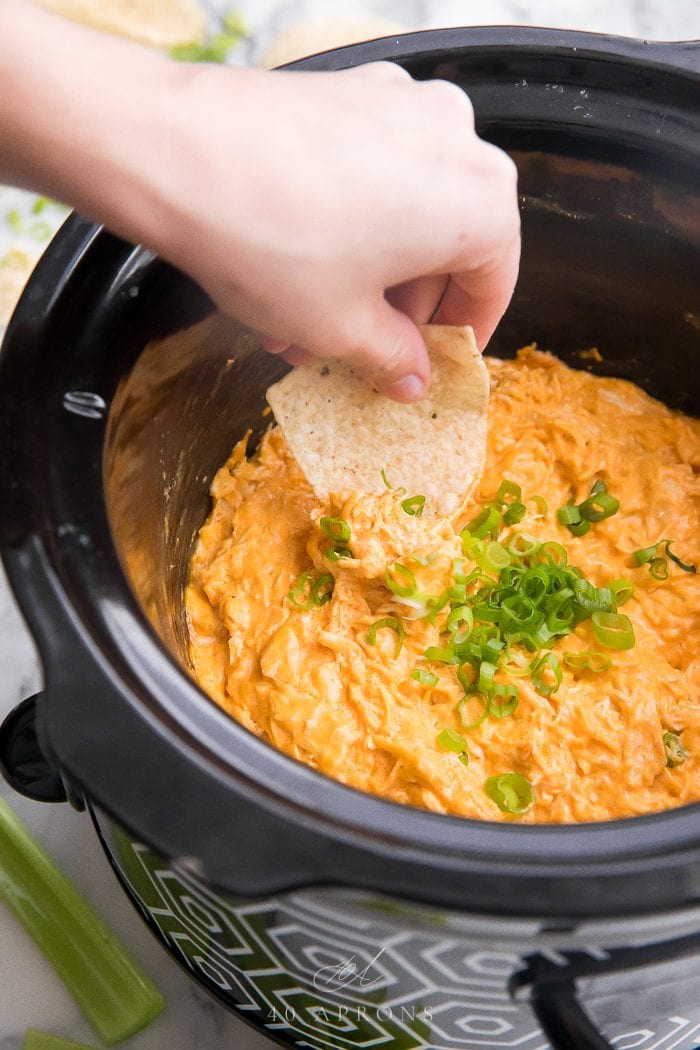 A tortilla chip scooping up dip from a slow cooker