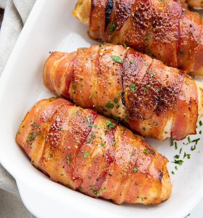Four Bacon wrapped chicken breasts in a baking dish