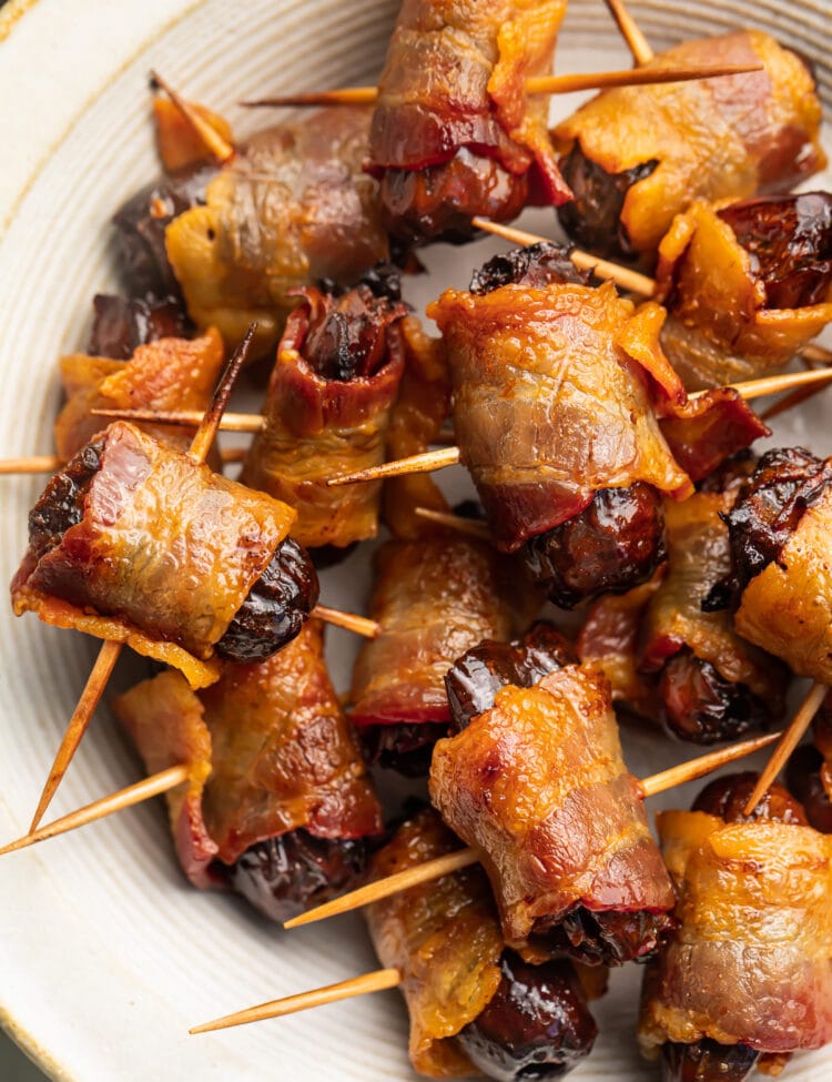 Bacon-wrapped dates, skewered by toothpicks, piled up in a large bowl.