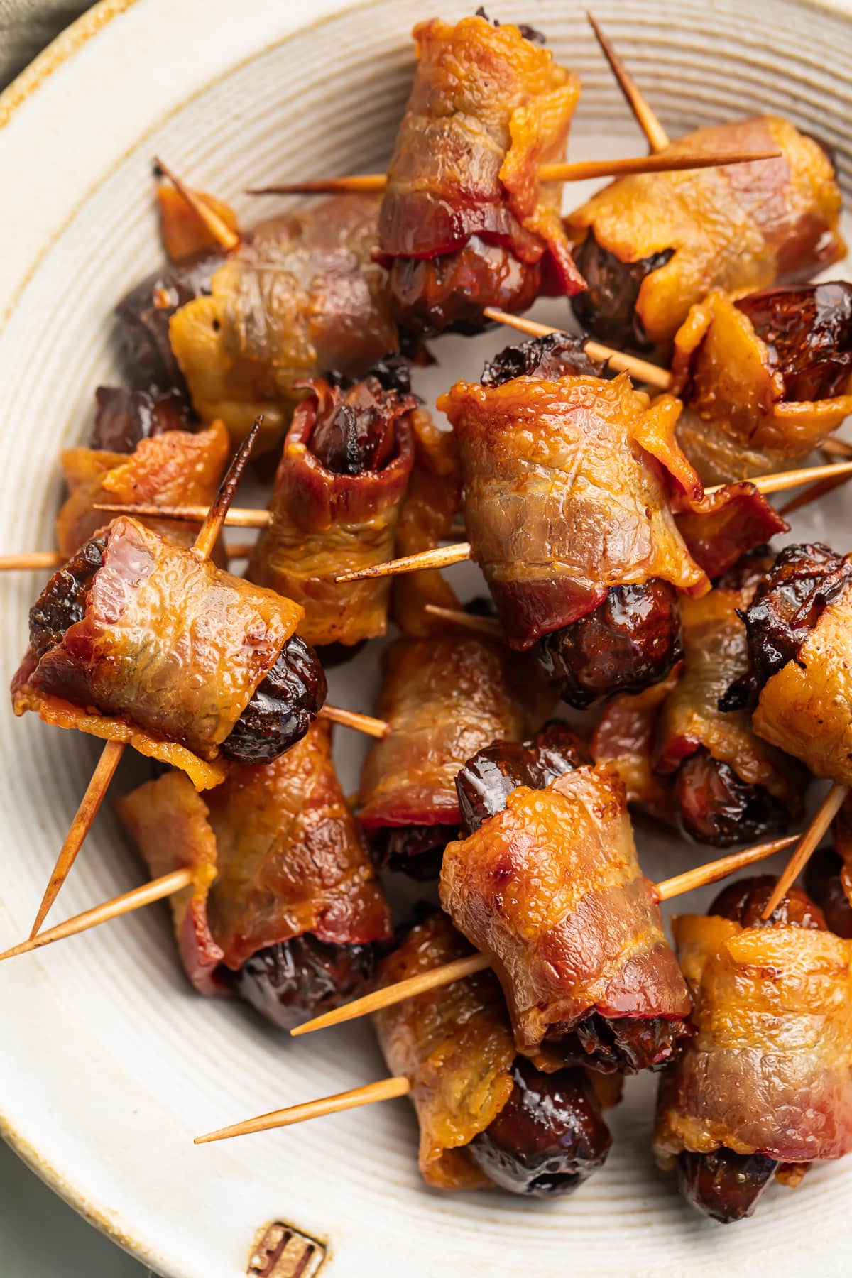 Bacon-wrapped dates, skewered by toothpicks, piled up in a large bowl.