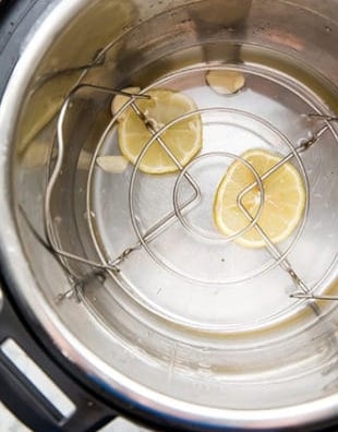 Lemon slices and water in an Instant Pot under a trivet