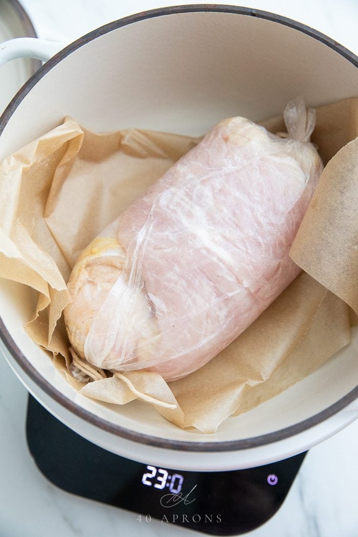 A turkey breast wrapped and laid on parchment in a pot