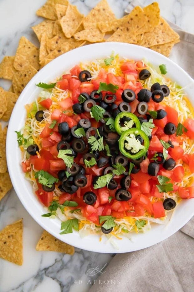 Taco dip in a white dish with tortilla chips around