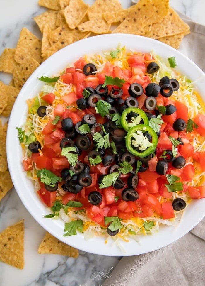 Taco dip in a white dish with tortilla chips around