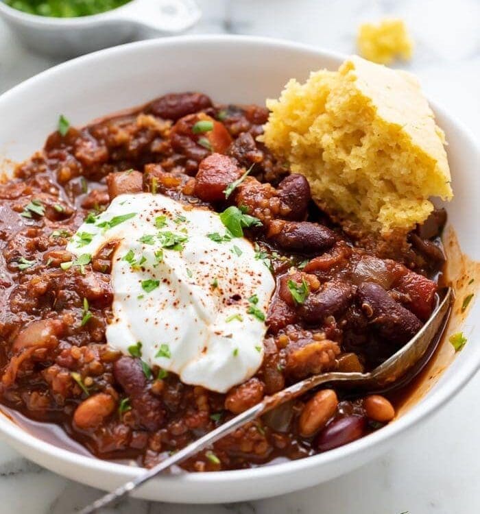 A bowl of vegan chili with a piece of cornbread