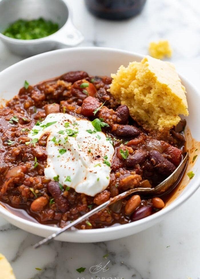 A bowl of vegan chili with a piece of cornbread