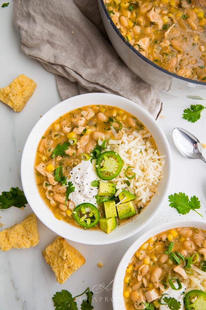 Two bowls of white bean chili on a white work surface