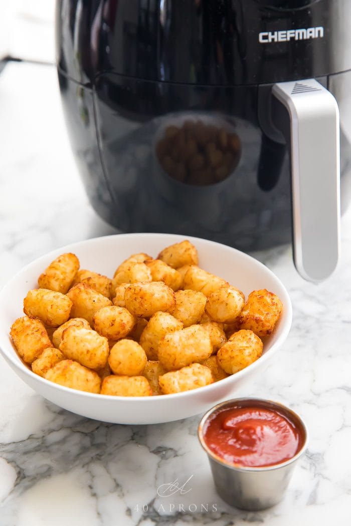 Tater tots in front of an air fryer