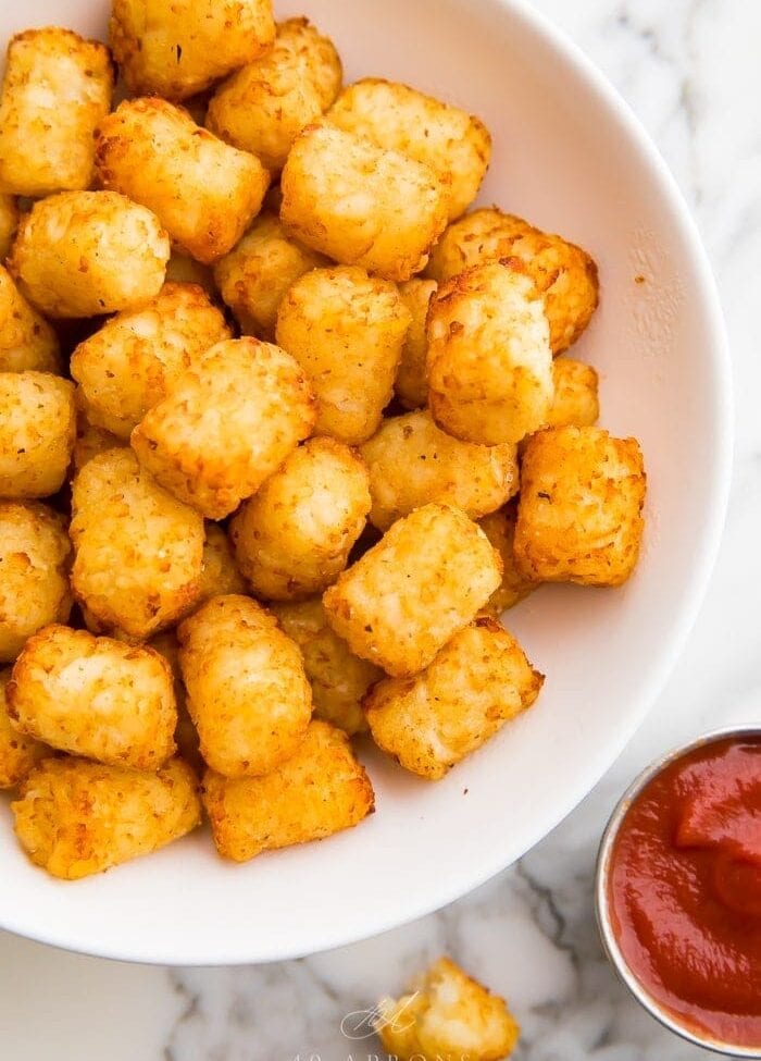 Air fruer tater tots served in a bowl with sauce