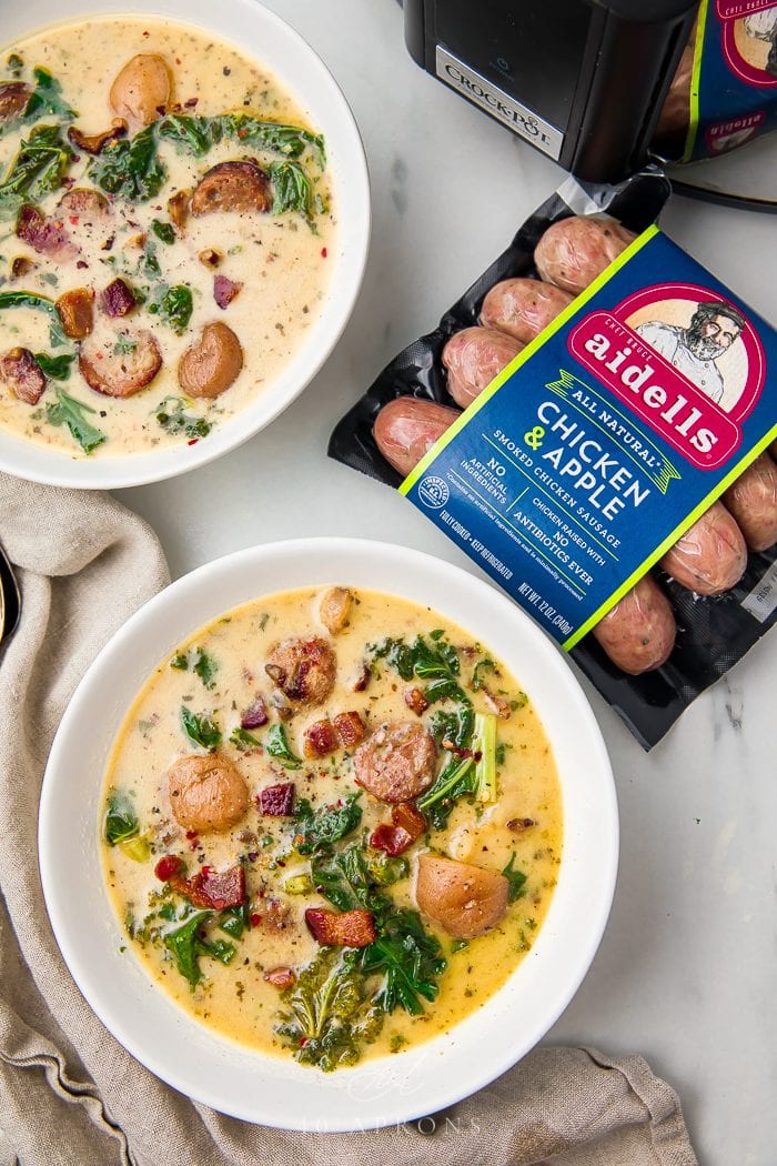 Two bowls of zuppa toscana next to the sausages used