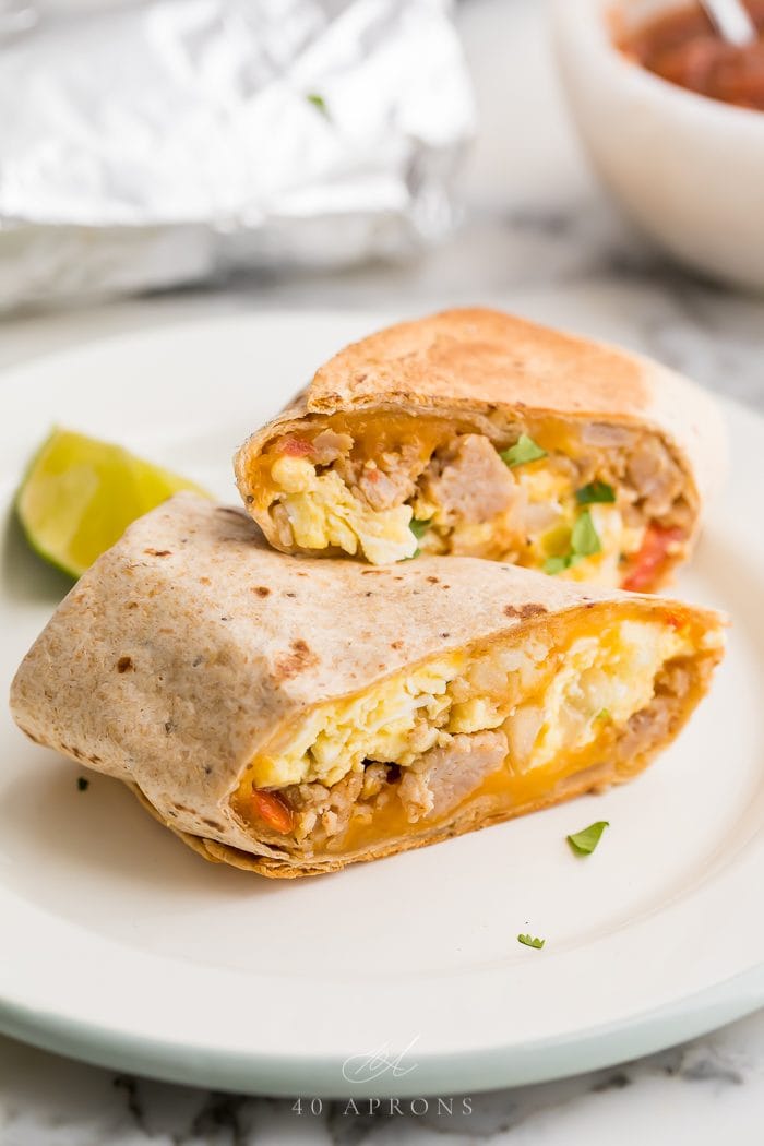 healthy whole wheat breakfast burrito filled with sausage, pico de gallo and scrambled egg on a white plate