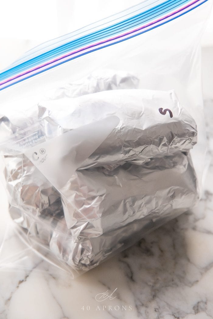 Freezer Breakfast Burritos wrapped in aluminum foil placed in a big zip-lock freezer bag
