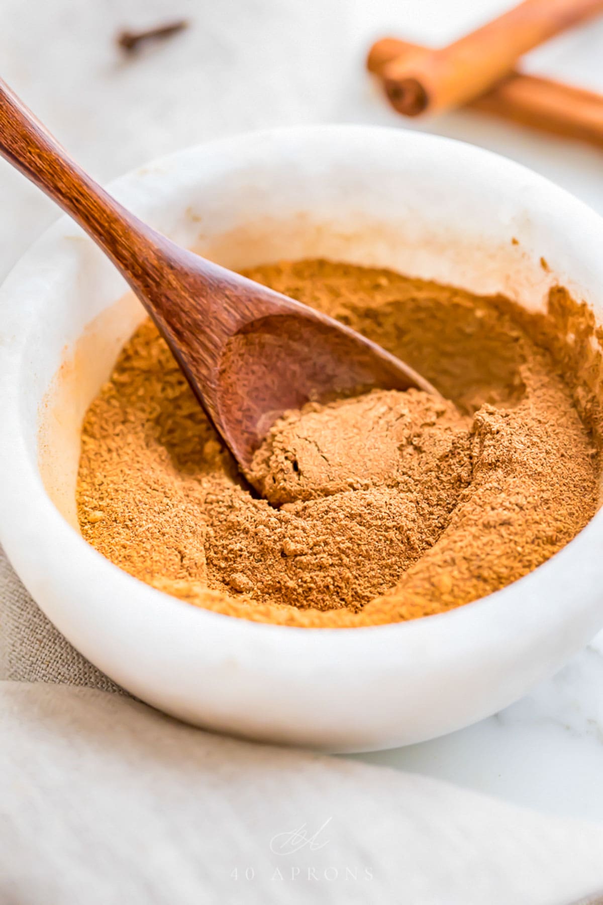 Homemade pumpkin pie spice blend in a small marble bowl with a small wooden spoon.